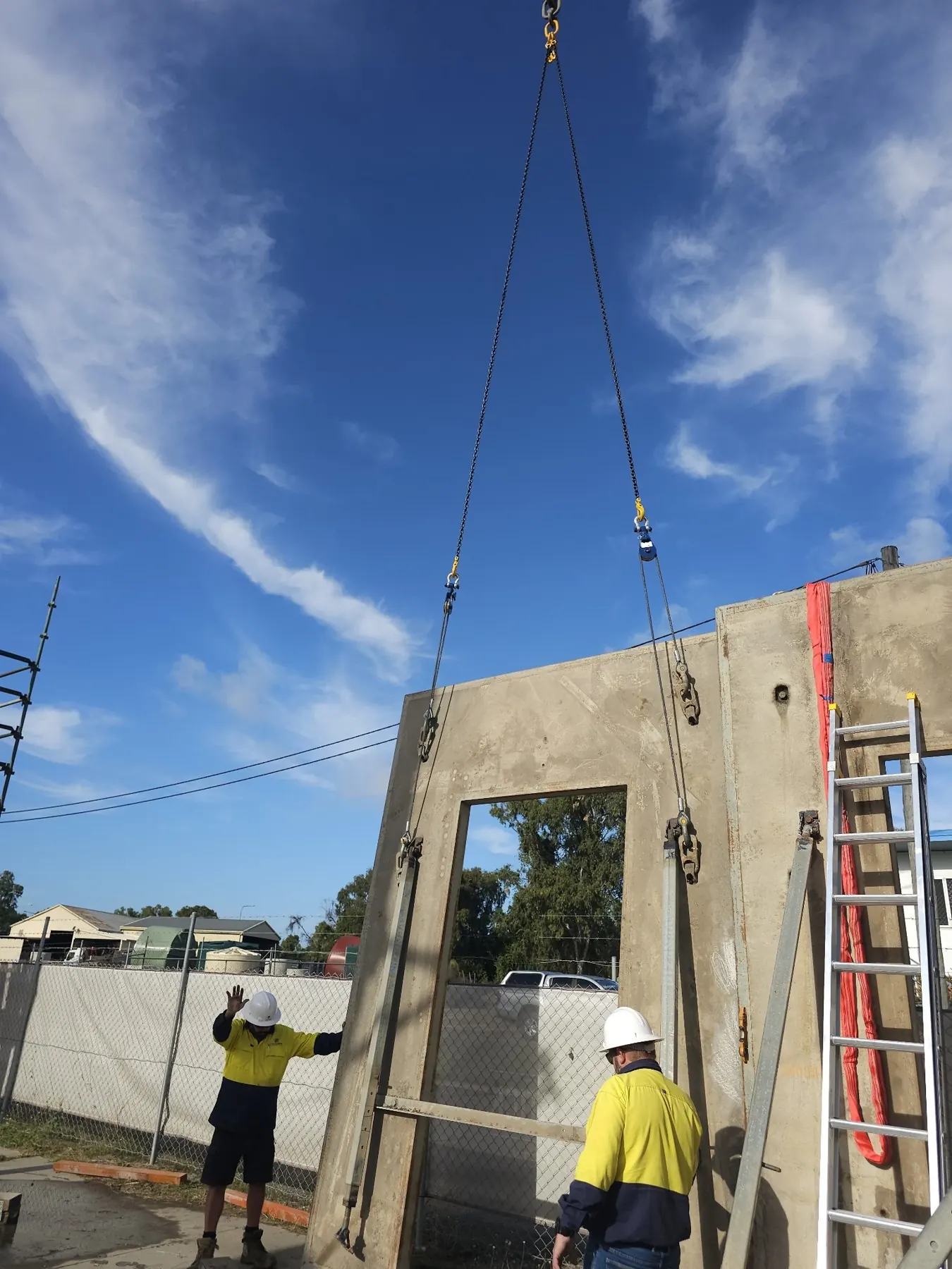 Concrete panel being lifted into place with a crew on tag lines